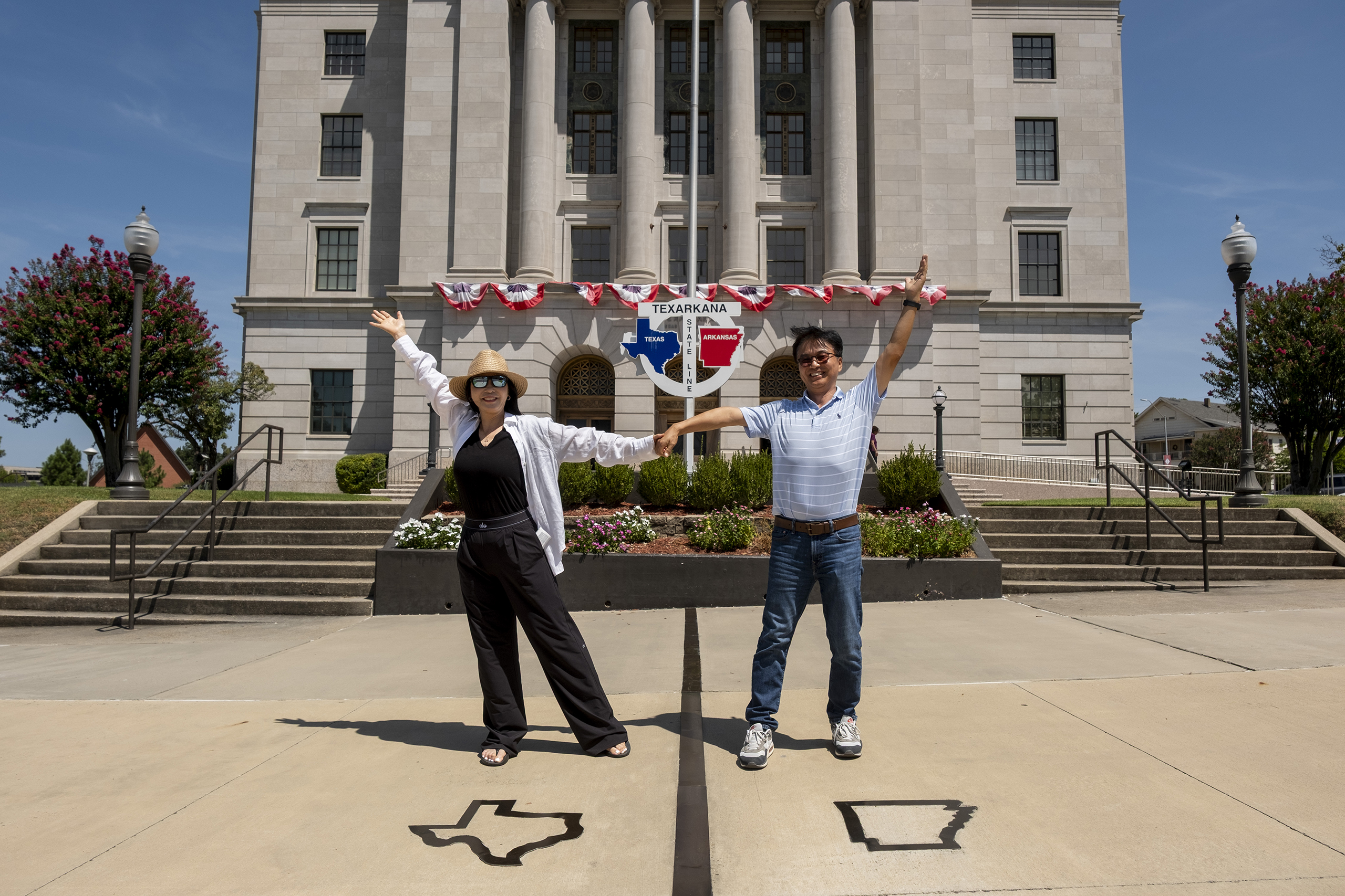 Mikyoung Hong and Cheoungjoon Lee of Korea hold hands while standing in different states at the State Line Post Office and Federal Building on the Texas/Arkansas border in downtown Texarkana on Wednesday. The massive Smackover Formation extends from Texas across Arkansas, Louisiana, Mississipi, alabama and Florida.