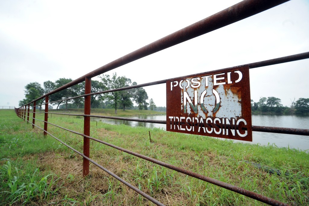 A long standing welded metal fence with posted signs blocking access to the Cutoff.
