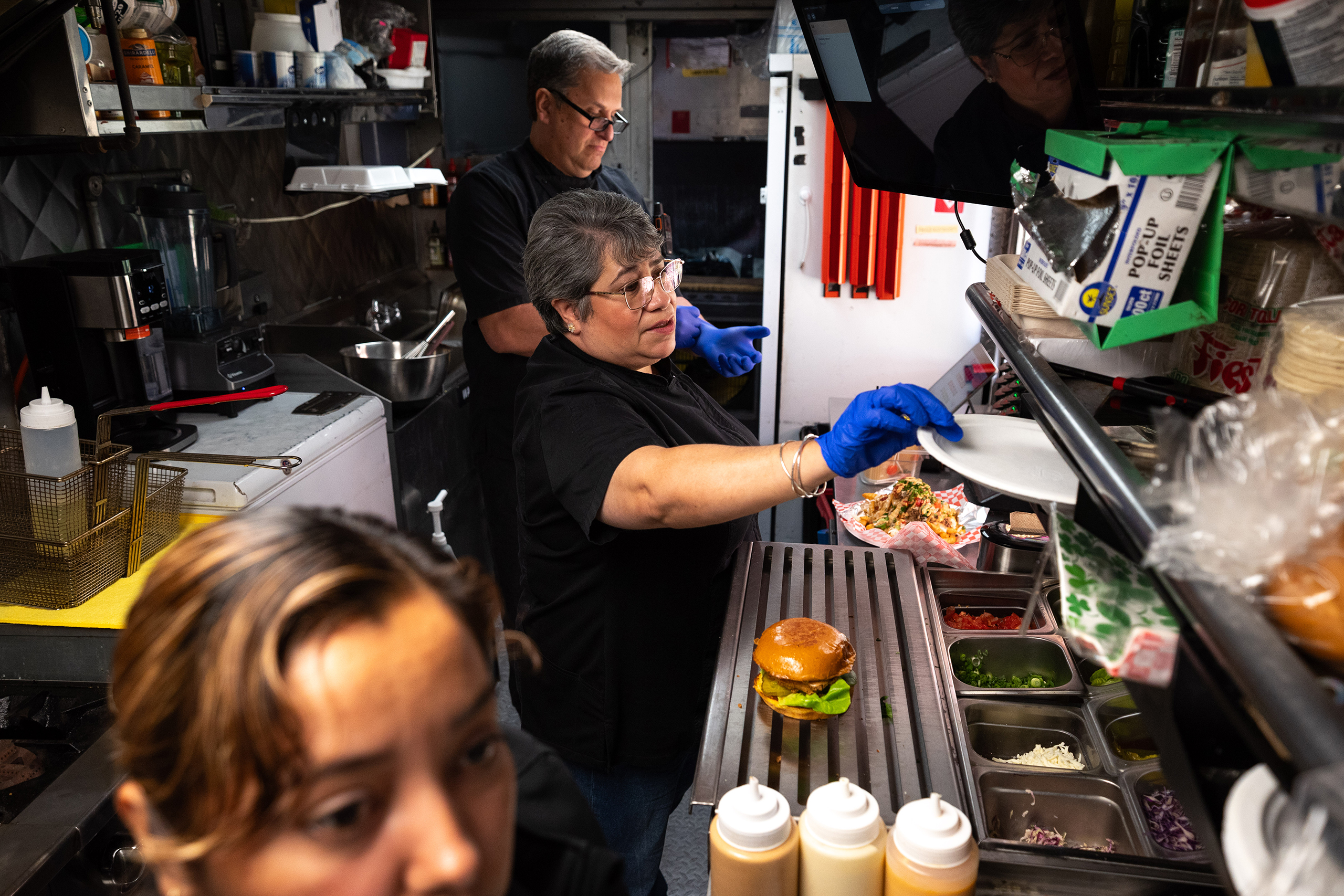 L-R: Edilma Pleitez, owner Eloisa Schessler and her husband Julio Schessler, working inside the food truck Eloisa&rsquo;s Kitchen, located at Klyde Warren Park near downtown Dallas, on March 12, 2026. HB 2844 requires for the entire state of Texas to adhere to the same food truck safety requirements and policies. This would allow for all trucks to follow the same rules, regardless of the different counties and cities that they are in. It would be easier for the people who own the food trucks, but it would force the cities, and counties to lose money.