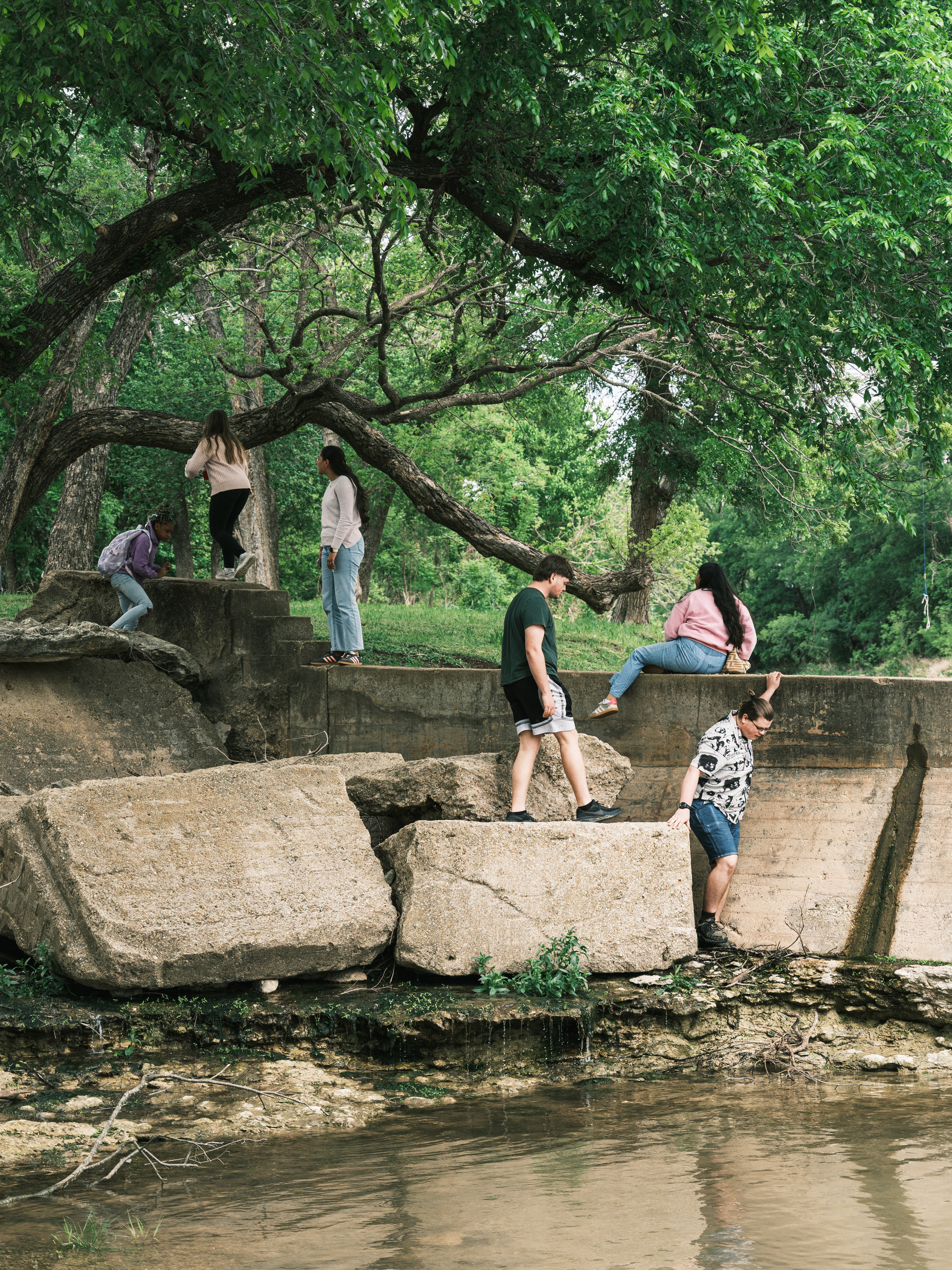 Kids play along a dam in the Middle Bosque River before Jimmy Dorrell and Kevin Brown baptize believers on Easter Sunday.