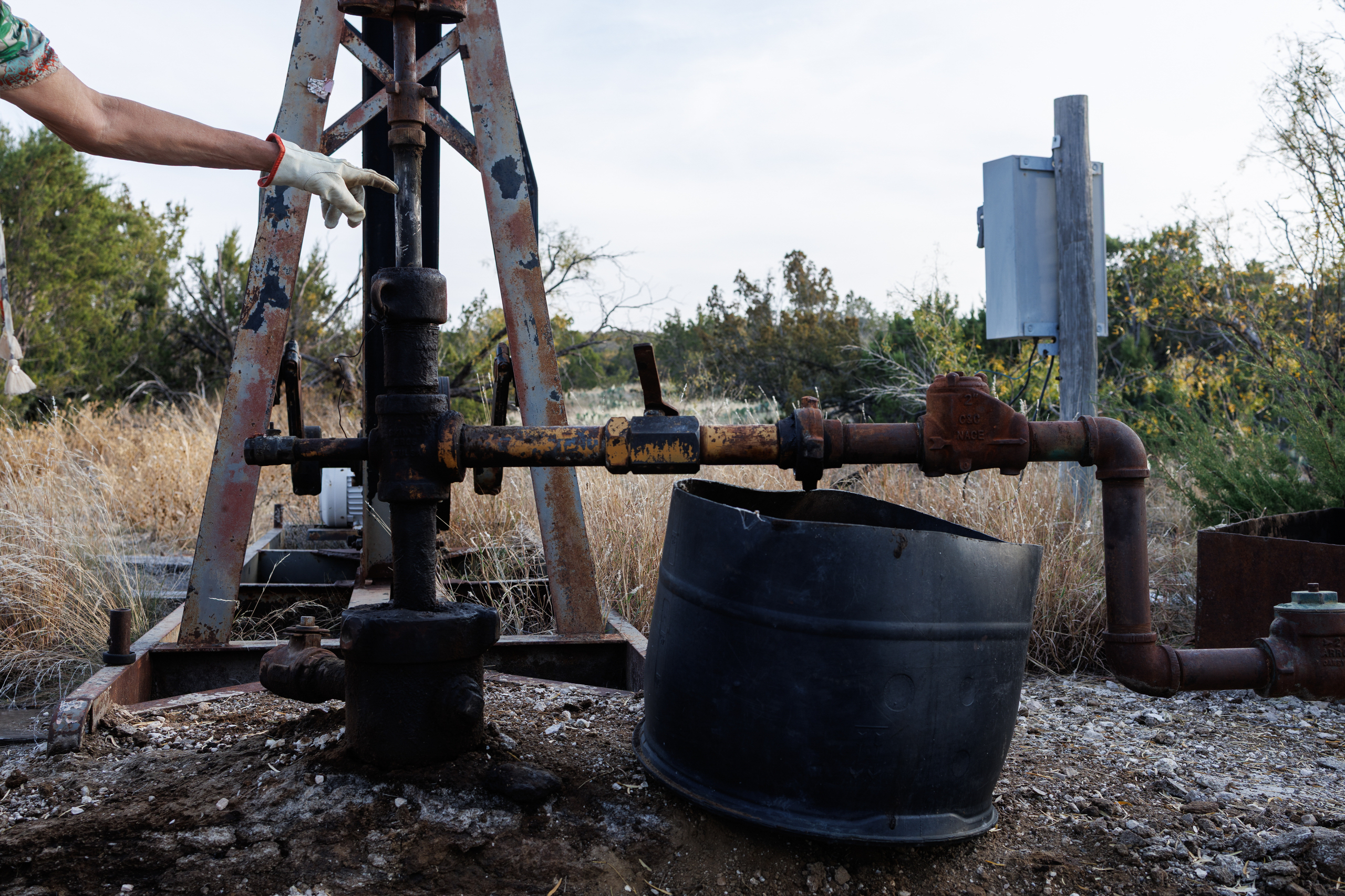 Jackie Lynn Chestnutt points to an oil well owned by Core Petro LLC which is in disrepair and leaking, on her property in Knickerbocker, Texas on Tuesday, November 18, 2025. A large number of orphan oil wells are dotted around her property, causing worry that ground water could be contaminated by leeching oil, produced water or chemicals.