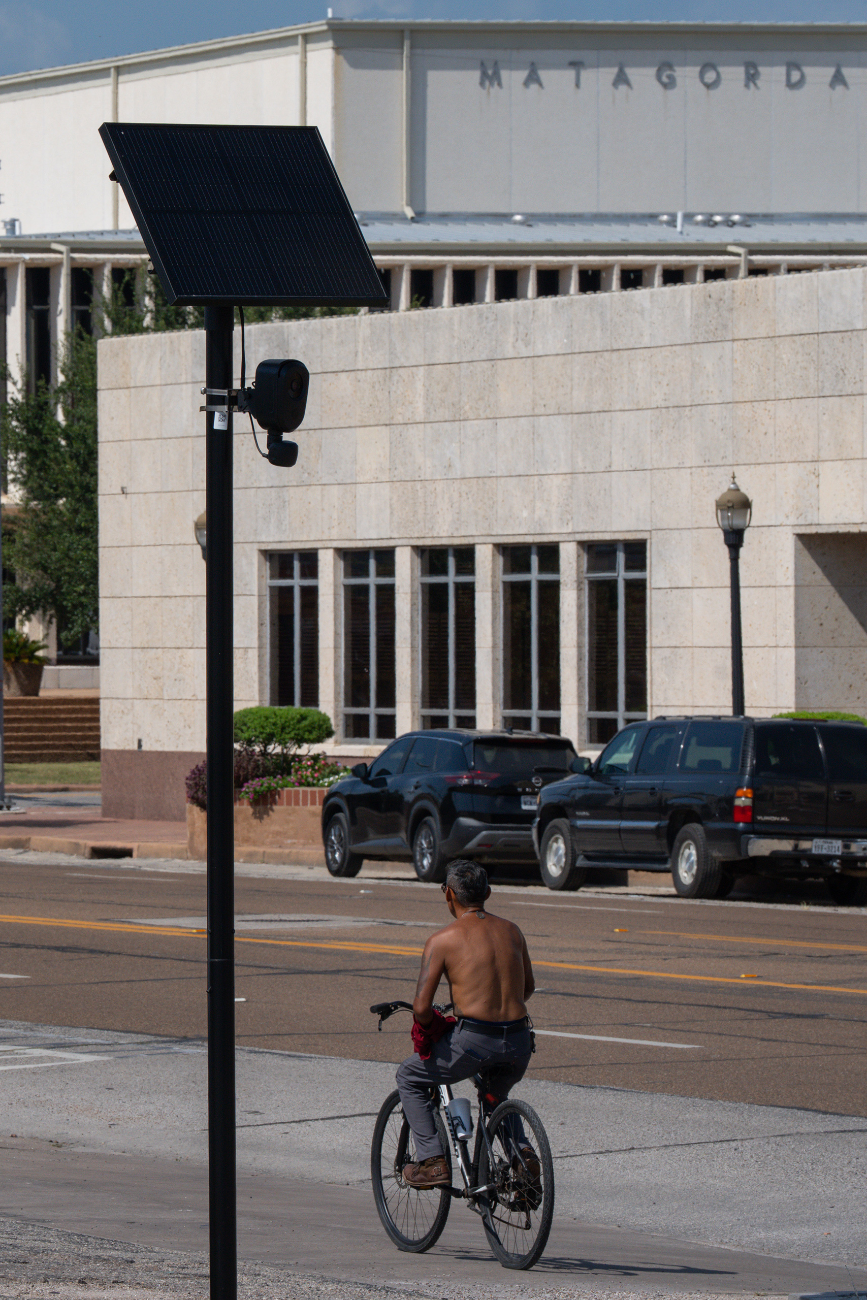 A man rides a bike past a Flock camera in Bay City on Sunday, Aug. 23, 2026.